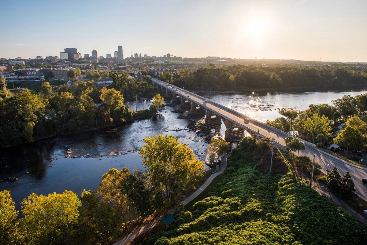 The Gervais Street bridge over the Congaree River at golden hour, with the Columbia skyline beyond